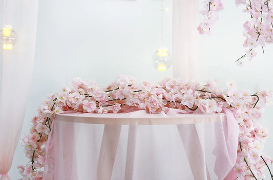 Guirlande de fleurs de cerisier artificielles roses posée sur une table pour décoration romantique.