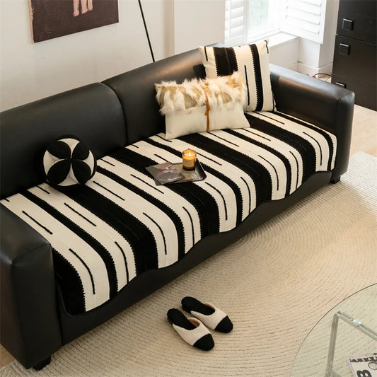 Housse de canapé asymétrique en chenille douce, posée sur un canapé droit moderne, dans un salon lumineux et élégant. Décoration intérieure