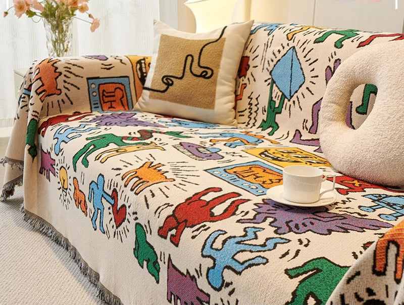 Housse de canapé double face en tissu doux beige et gris, posée sur un canapé moderne avec coussins assortis – couverture complète et décorative. Décoration intérieure