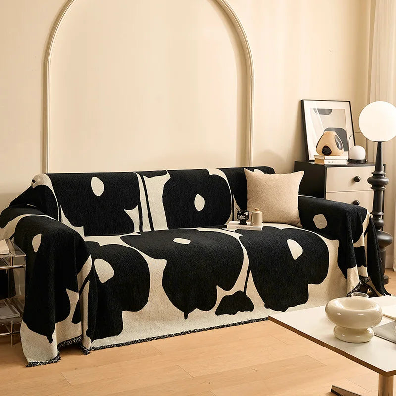 Housse de canapé en chenille style français, bordée de pompons, posée sur un canapé lumineux dans un salon raffiné et cosy. Décoration intérieure