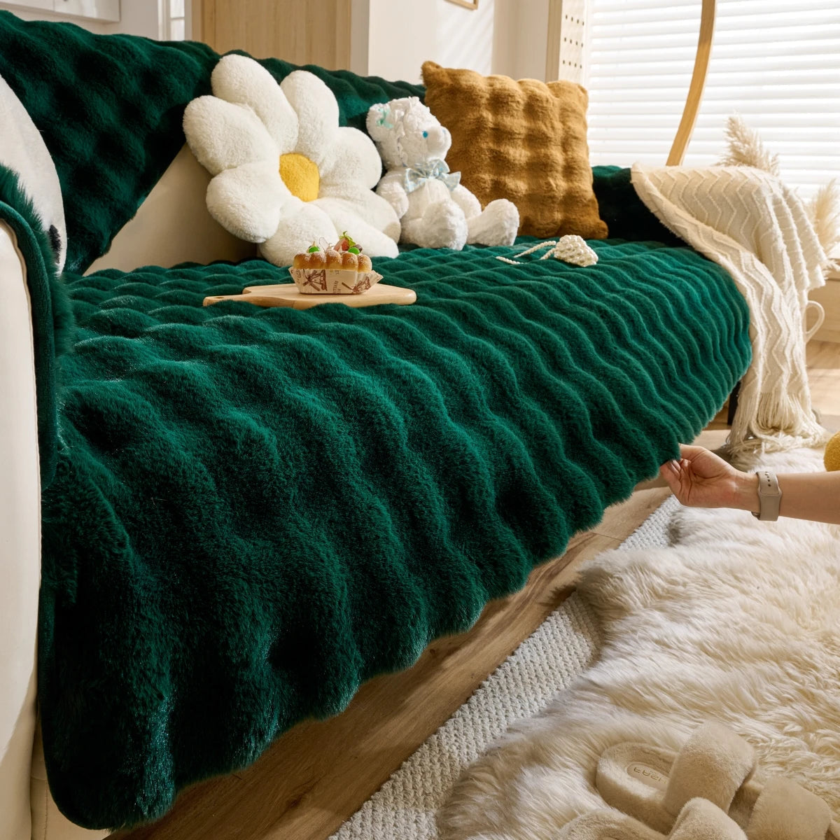 Housse de canapé en peluche  effet fourrure de lapin sur canapé 3 places dans salon moderne avec coussins assortis et tapis douillet. Décoration intérieure