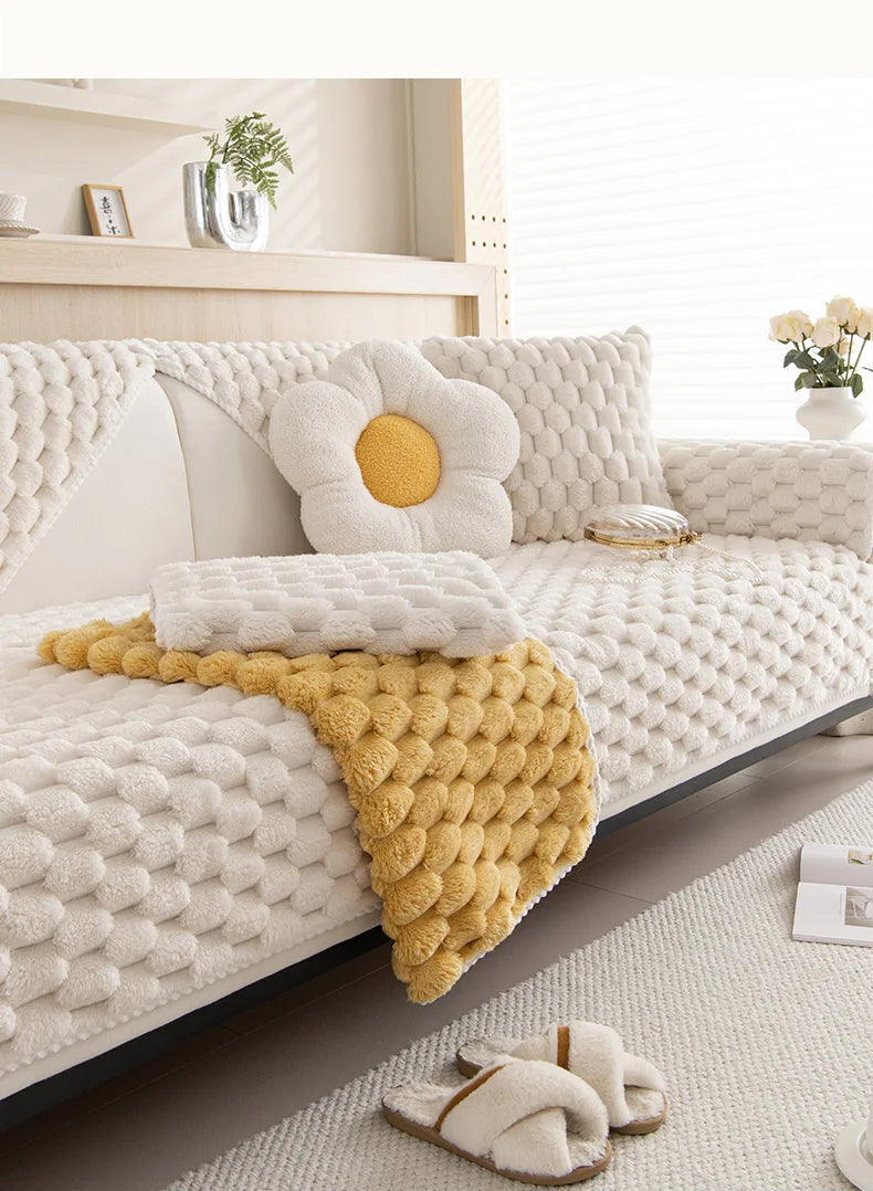 Housse de canapé en peluche épaisse, douce et antidérapante, posée sur un canapé sectionnel dans un salon chaleureux d’hiver. Décoration intérieure