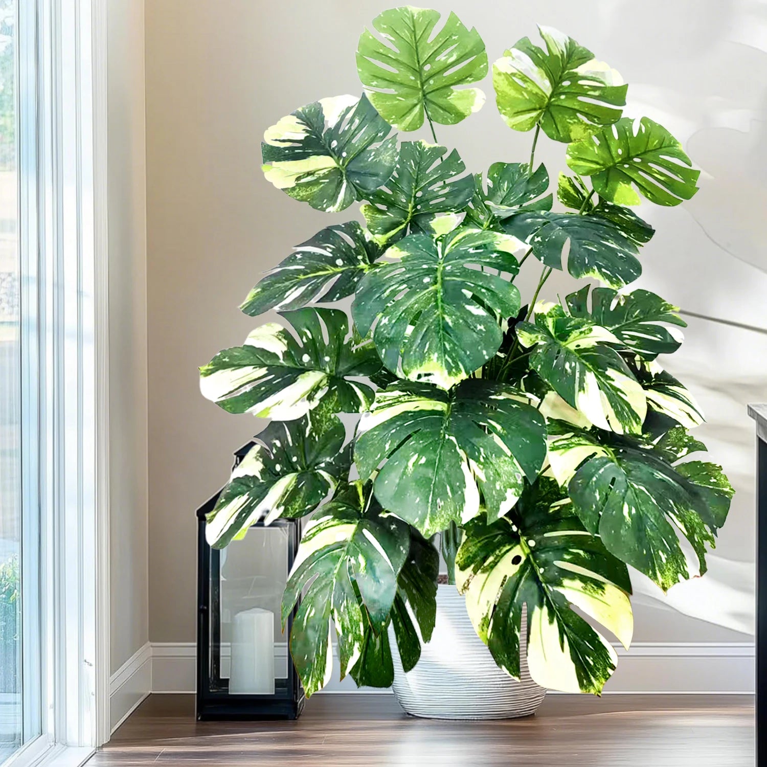 Plante artificielle Monstera 110 cm au feuillage vert luxuriant, posée dans un intérieur moderne avec mobilier bois et lumière naturelle