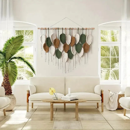 Tapisserie murale vert et marron en macramé avec feuilles et plumes  tissées à la main, suspendue dans un intérieur bohème et naturel - Décoration intérieure
